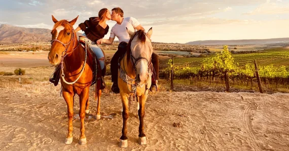 Couple enjoying a horseback riding experience overlooking Temecula Valley vineyards with Kentina Hospitality