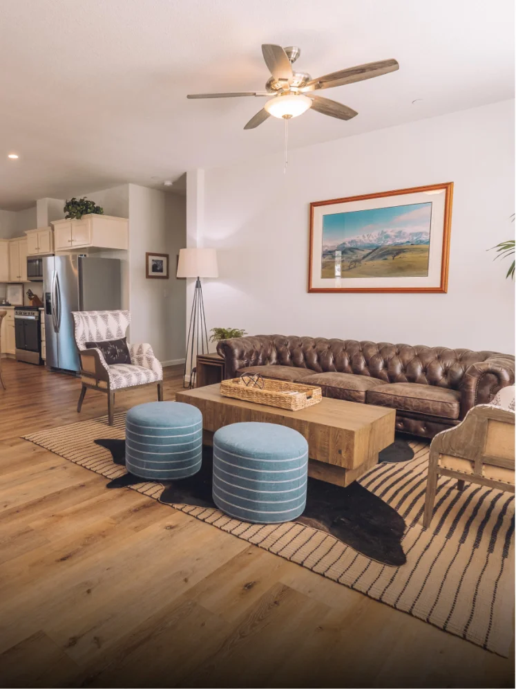 Spacious living room with leather sofa, wood flooring, and open kitchen in a Temecula vacation rental property