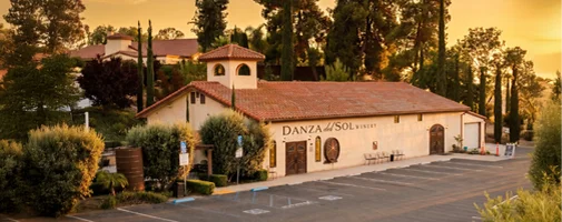Exterior view of Danza del Sol Winery surrounded by vineyards and rolling hills in Temecula Wine Country at sunset