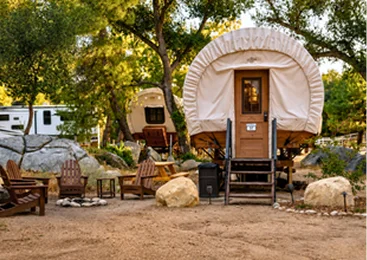 Luxury covered wagon glamping accommodation with outdoor seating and fire pit area in Temecula Valley's scenic countryside retreat