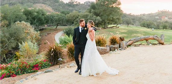 Bride and groom sharing a moment beside a scenic championship golf course in Temecula Valley during an outdoor wedding celebration surrounded by rolling hills and natural landscape