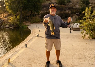 Guest showing a freshly caught fish during a lakeside fishing experience at a Temecula Valley resort with waterfront recreation and outdoor activities available for visitors