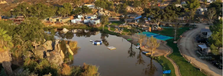 Aerial view of a lakeside resort featuring cabins, waterfront recreation, outdoor amenities, and scenic countryside landscapes in Temecula Valley