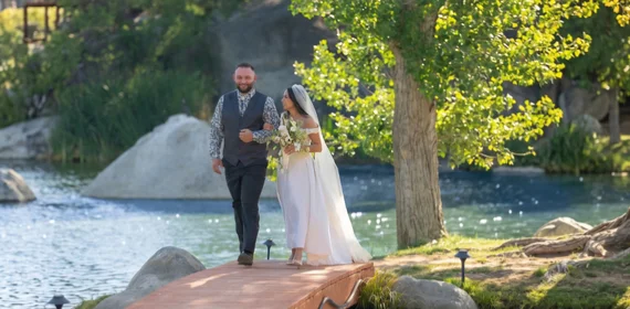 Bride and groom walking along a lakeside ceremony path during an outdoor wedding celebration at a scenic Temecula Valley resort venue surrounded by natural beauty and waterfront views