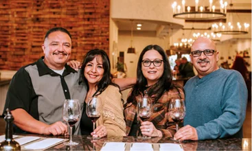 Friends enjoying a wine tasting experience together at a Temecula Wine Country winery with glasses of red wine and vineyard hospitality ambiance