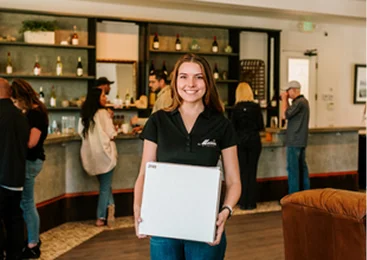 Winery team member holding a wine shipment package inside a Temecula Wine Country tasting room and hospitality center